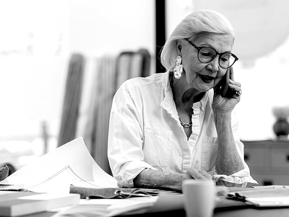 black and white image on an older buinsess woman taking a phone call at her desk